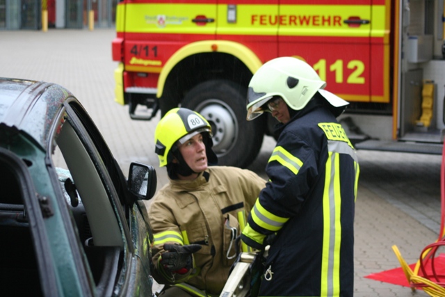 Zwei Feuerwehrleute bei einer Rettungsübung neben einem Auto.