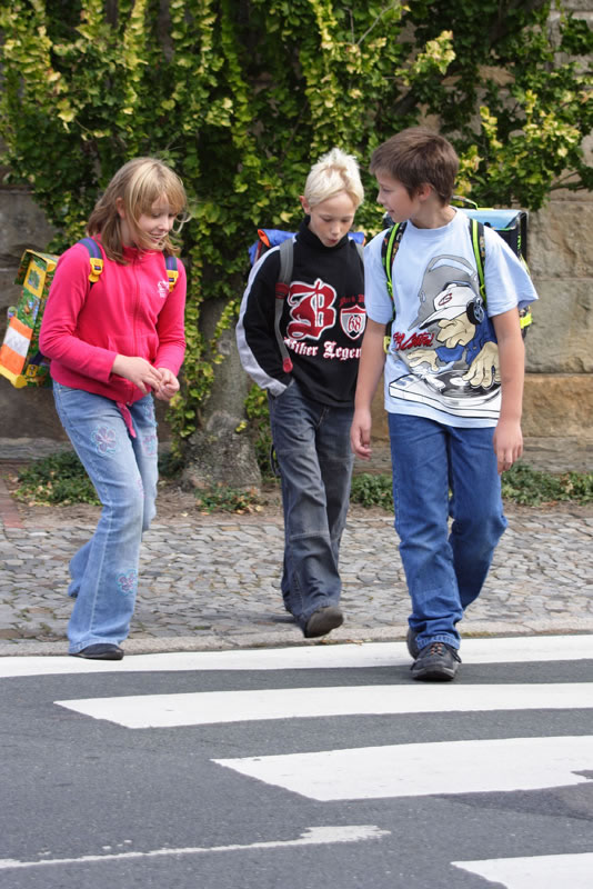 Kinder überqueren Zebrastreifen.