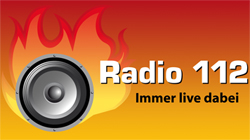 Das Bild zeigt das Logo von Radio 112, bestehend aus einem großen Lautsprecher vor einem stilisierten Flammenhintergrund. Rechts neben dem Lautsprecher steht in weißer Schrift der Schriftzug 'Radio 112' und darunter in kleinerer Schrift 'Immer live dabei'. Der Hintergrund des Logos ist ein Farbverlauf von Rot zu Orange, der Flammen symbolisiert. Das Bild vermittelt Energie und Dynamik, passend zu einem Radiosender, der möglicherweise in Notfällen oder bei Sicherheitsfragen sendet, was im Kontext von Unfallkasse NRW mit Arbeitsschutz und Prävention zu tun haben könnte.
