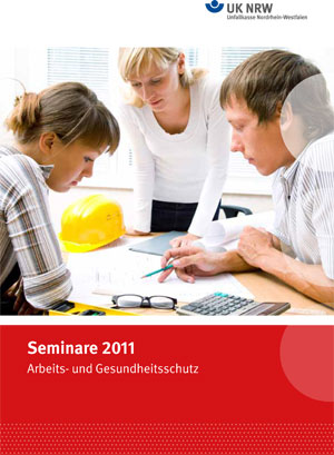 Drei Personen stehen an einem Tisch und scheinen Baupläne oder Dokumente zu besprechen. Auf dem Tisch liegen ein gelber Schutzhelm, ein Taschenrechner und einige Papiere. Die Männer und Frauen scheinen ernsthaft und konzentriert bei der Arbeit zu sein. Der obere Rand des Bildes zeigt das Logo der Unfallkasse Nordrhein-Westfalen, passend zu einem Seminarangebot über Arbeits- und Gesundheitsschutz im Jahr 2011.