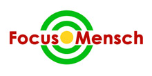Das Bild zeigt das Logo der Initiative 'Focus Mensch', bestehend aus einem grünen Kreis mit konzentrischen Ringen und dem Text 'Focus Mensch' in Rot mit einem gelben Punkt als Bindeglied zwischen den Worten. Es symbolisiert die Fokussierung auf Menschlichkeit im Kontext von Arbeitsschutz und Prävention der Unfallkasse NRW.