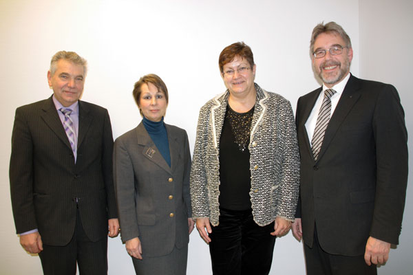 Vier Personen stehen nebeneinander in Anzügen.