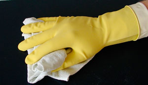 Hand mit gelbem Handschuh reinigt Oberfläche.