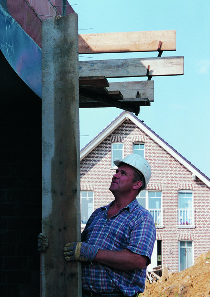 Bauarbeiter mit Helm richtet Betonplatte an.