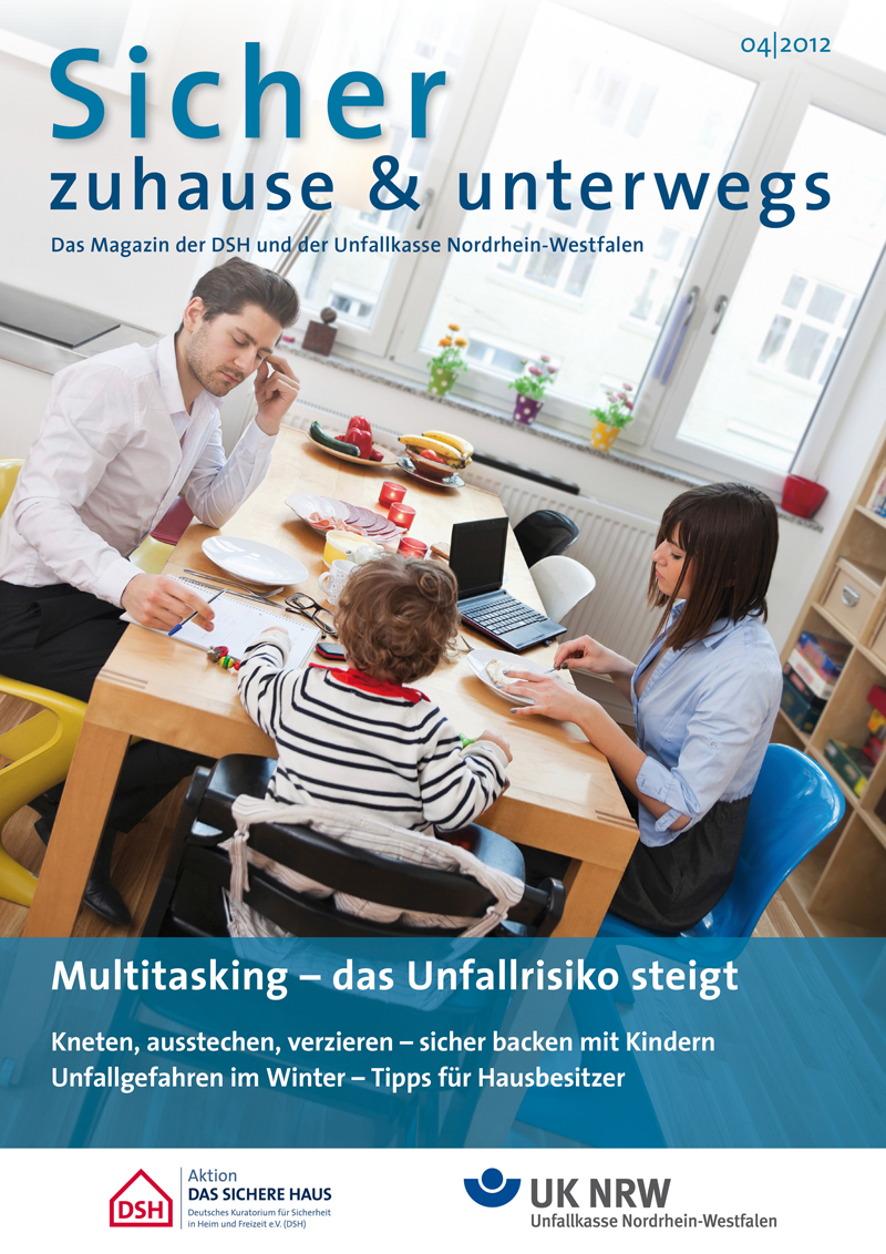Eine Frau sitzt mit zwei Kindern an einem Tisch im Wohnzimmer. Sie backen gemeinsam Plätzchen, jeder ist beschäftigt mit Kneten und Ausstechen. Auf dem Tisch liegen verschiedene Backutensilien und Zutaten. Im Hintergrund auf dem Tisch stehen ein Laptop und zweites Backblech. Der Titel des Magazins lautet 'Sicher zuhause & unterwegs', herausgegeben von der Unfallkasse Nordrhein-Westfalen, mit Schwerpunkt auf Arbeitsschutz und Prävention im heimischen Umfeld.