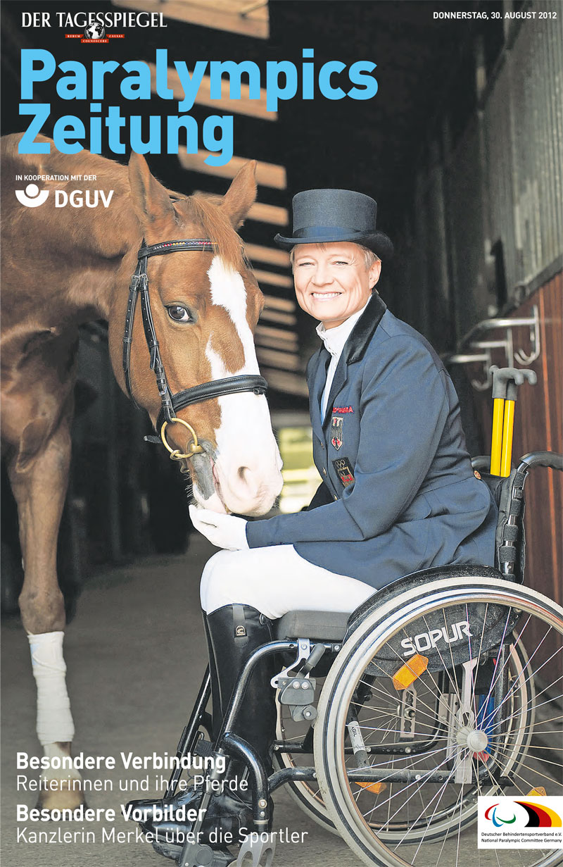 Eine Frau im Rollstuhl trägt Reitkleidung und umarmt ein Pferd in einem Stall. Sie lächelt, während sie die Zügel des Pferdes hält. Die Umgebung ist eine Holzscheune, die auf Arbeitsschutzmaßnahmen im Reitsport hinweist. Das Bild thematisiert das Thema Barrierefreiheit und Inklusion im Sport, insbesondere im Rahmen von Veranstaltungen wie den Paralympics. Die Darstellung hebt die Bedeutung von Prävention und Sicherheit im Sport für Menschen mit Behinderung hervor.