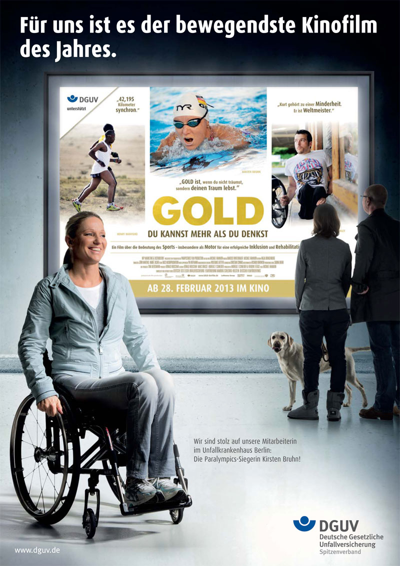 Plakat zur Werbung für den Film 'Gold - Du kannst mehr als du denkst'. Im Vordergrund sitzt eine junge Frau im Rollstuhl lächelnd. Hinter ihr ist ein großer Filmplakat mit Szenen einer Schwimmerin im Wettkampf sowie einem Mann mit Prothese beim Lauf. Oben steht der Text: 'Für uns ist es der bewegendste Kinofilm des Jahres.' Im unteren Bereich erkennt man Logos der DGUV und den Hinweis auf die Paralympics-Siegerin. Es deutet auf die Themen Arbeitsschutz und Prävention hin und verdeutlicht die Bedeutung von Inklusion und Rehabilitation.