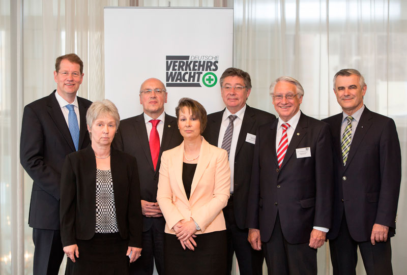 Das Bild zeigt sieben Personen, die vor einem Banner mit der Aufschrift 'Deutsche Verkehrswacht' stehen. Die Personen sind in geschäftlicher Kleidung gekleidet und blicken in Richtung Kamera. Das Banner im Hintergrund deutet auf ein Treffen im Kontext von Verkehrssicherheit und Präventionsarbeit hin. Der Zusammenhang mit der Unfallkasse NRW betont den Fokus auf Arbeitsschutzmaßnahmen.