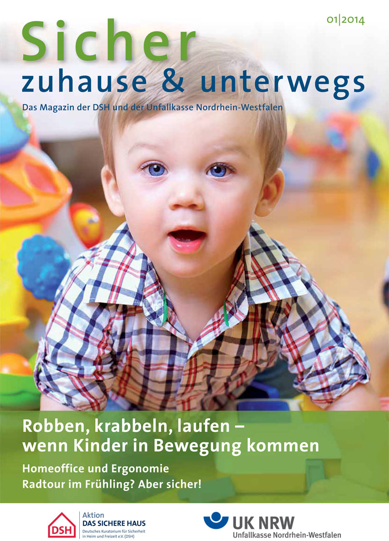 Das Cover des Magazins 'Sicher zuhause & unterwegs' zeigt ein kleines Kind in kariertem Hemd, das auf allen Vieren auf einem Holzboden krabbelt. Im Hintergrund sind unscharf Spielzeug und weitere Details eines Wohnraums zu erkennen. Der obere Textbereich beinhaltet den Magazintitel mit Schwerpunkt auf Sicherheit und Prävention im Alltag. Themen: Robben, krabbeln, laufen – wenn Kinder in Bewegung kommen, Homeoffice und Ergonomie, Radtour im Frühling. Herausgeber ist die Unfallkasse Nordrhein-Westfalen in Zusammenarbeit mit der Aktion Das Sichere Haus.