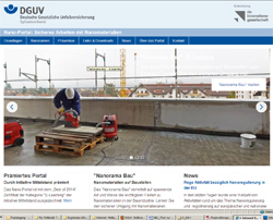 Ein Bauarbeiter steht auf einem Gerüst und bearbeitet Holzplatten. Er trägt einen Schutzhelm und eine Warnweste. Im Hintergrund sind Baukräne und Gebäude zu sehen. Links im Bild befindet sich ein rotes Sicherheitsgerät. Das Bild dient der Förderung von Arbeitsschutz und Unfallprävention auf Baustellen und ist Teil des Online-Portals der Deutschen Gesetzlichen Unfallversicherung.