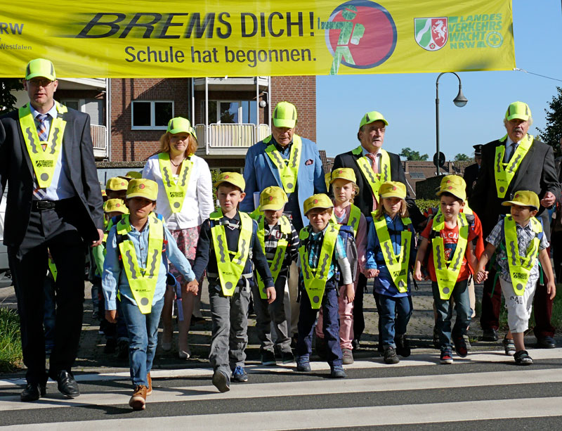 Das Bild zeigt Schulkinder mit Verkehrsminister Michael Groschek beim Überqueren einer Straße.