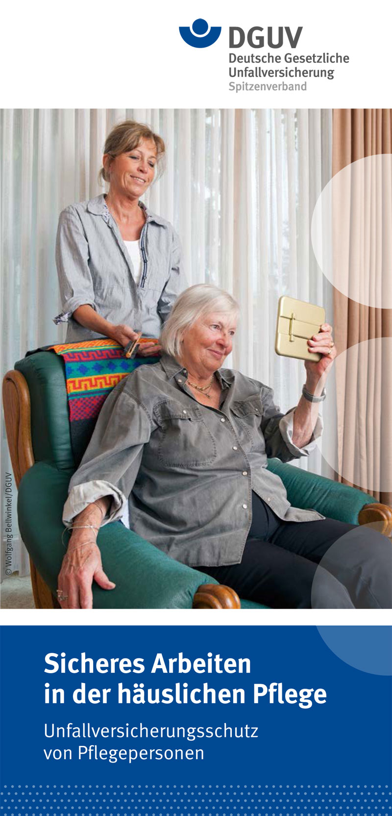 Zwei Frauen in einem Wohnzimmer: Eine jüngere Frau steht hinter einem Sessel und hilft einer älteren Frau, die im Sessel sitzt, mit einem Smartphone. Die ältere Frau hält das Telefon in der Hand und schaut auf den Bildschirm. Das Bild vermittelt den Aspekt der Unterstützung und zeigt das Thema der häuslichen Pflege. Im oberen Teil befindet sich das Logo der DGUV. Darunter steht der Text: 'Sicheres Arbeiten in der häuslichen Pflege - Unfallversicherungsschutz von Pflegepersonen'.