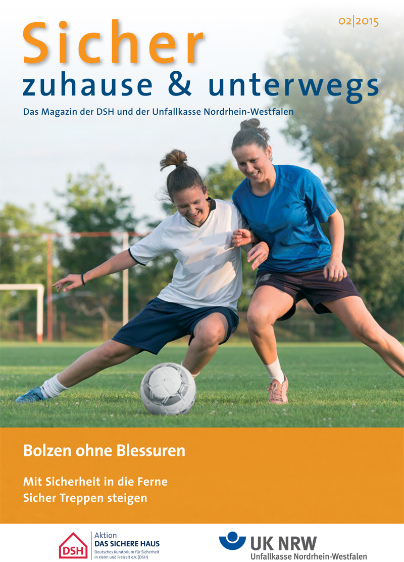 Das Titelbild des Magazins zeigt zwei Frauen, die auf einem Fußballfeld um den Ball kämpfen. Im Hintergrund ist ein gepflegter Rasenplatz zu sehen. Der obere Teil des Covers trägt den Titel 'Sicher zuhause & unterwegs', veröffentlicht von der DSH und der Unfallkasse Nordrhein-Westfalen. Unten auf dem Cover stehen die Schlagzeilen 'Bolzen ohne Blessuren', 'Mit Sicherheit in die Ferne' und 'Sicher Treppen steigen'. Das Thema bezieht sich auf Arbeitsschutz und Verletzungsprävention im Rahmen von Sport- und Alltagsaktivitäten.