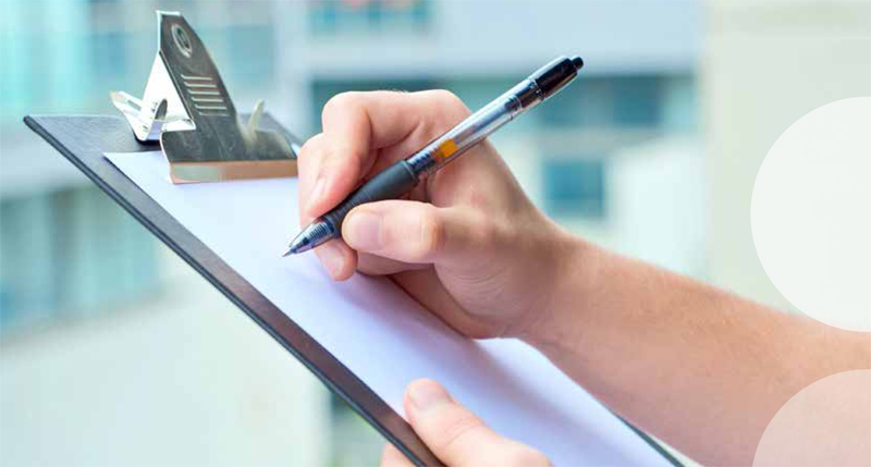 Person füllt mit Stift ein Klemmbrett aus.