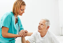 Pflegekraft hilft älterem Mann beim Aufstehen.