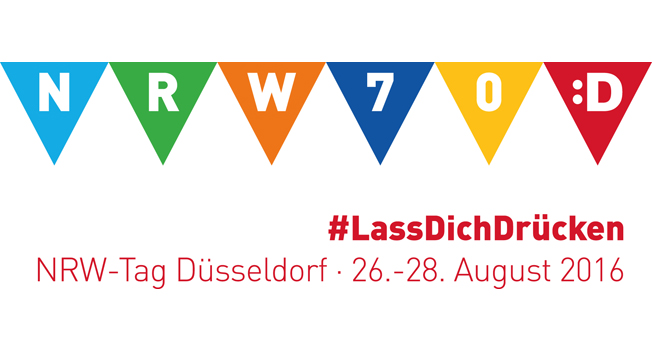 Das Bild zeigt ein Banner mit bunten Wimpeln, die die Buchstaben 'NRW' und die Zahl '70' tragen. Auf der rechten Seite ist ein gelbes Smiley-Gesicht. Unter dem Banner steht der Hashtag '#LassDichDrücken' in roter Schrift. Darunter sind die Worte 'NRW-Tag Düsseldorf · 26.-28. August 2016' ebenfalls in Rot. Das Bild könnte auf Veranstaltungen der Unfallkasse NRW im Rahmen von Arbeitsschutz und Prävention hinweisen.