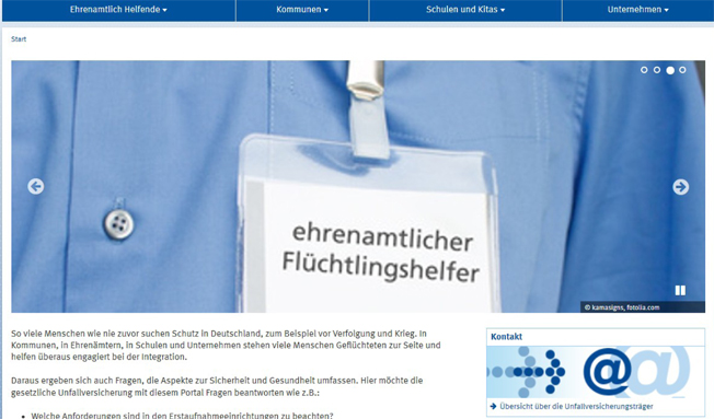 Das Bild zeigt eine Nahaufnahme eines Namensschildes, das von einer Person getragen wird. Auf dem Schild steht 'ehrenamtlicher Flüchtlingshelfer'. Der Hintergrund ist verschwommen, die Person trägt ein blaues Hemd. Das Bild ist Teil einer Webseite der Unfallkasse NRW, die sich mit dem Thema Arbeitsschutz und Prävention im Bereich ehrenamtliches Engagement beschäftigt.