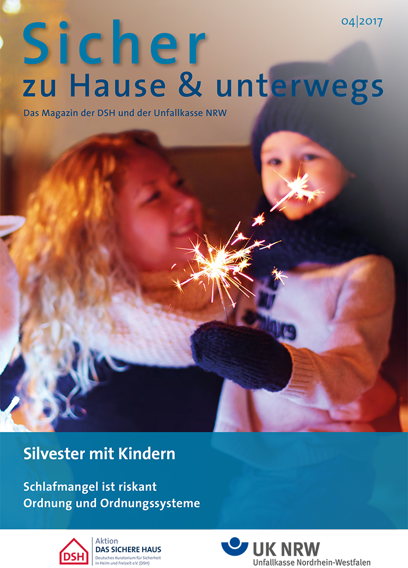 Das Cover des Magazins 'Sicher zu Hause & unterwegs' von 04/2017 der Unfallkasse NRW zeigt eine Frau, die ein Kind auf dem Arm hält. Beide tragen Winterkleidung und halten eine brennende Wunderkerze in der Hand. Oben steht der Titel in großen Buchstaben, unten Hinweise zur Ausgabenummer und weitere Themen wie 'Silvester mit Kindern', 'Schlafmangel ist riskant' und 'Ordnung und Ordnungssysteme'. Die Publikation bezieht sich auf Arbeitsschutz und Prävention.