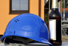 Blauer Schutzhelm und verschlossene Bierflasche auf einem Tisch.