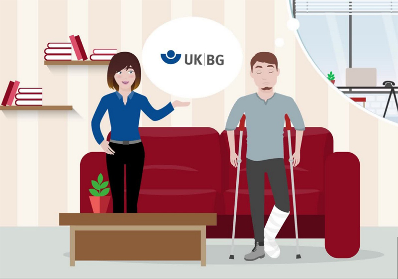 Eine Frau in blauem Hemd spricht mit einem Mann, der auf Krücken steht und dessen Bein eingegipst ist. Sie befindet sich in einem Wohnzimmer mit rotem Sofa, Pflanzen und Büchern. Ein Logo der Unfallkasse NRW schwebt in einer Sprechblase über ihr, was auf ein Gespräch über Arbeitsschutz und Prävention hindeutet. Im Hintergrund ist ein Fenster mit Blick auf einen Schreibtisch zu sehen.