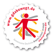 Das Bild zeigt das Logo der Gemeinsamen Deutschen Arbeitsschutzstrategie. Im Zentrum ist eine stilisierte Figur, die in verschiedenen Rot- und Grautönen dargestellt ist. Um die Figur herum steht in roter Schrift die Website-Adresse 'www.gdabewegt.de'. Unten sind die Worte 'Gemeinsame Deutsche Arbeitsschutzstrategie Arbeitsprogramm MSE' zu lesen. Das Logo hat eine gezackte äußere Form wie ein Stempel. Ziel ist die Förderung von Arbeitsschutz und Prävention, wichtige Themen für die Unfallkasse NRW.
