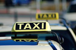 Zwei Taxi-Schilder auf parkenden Autos.