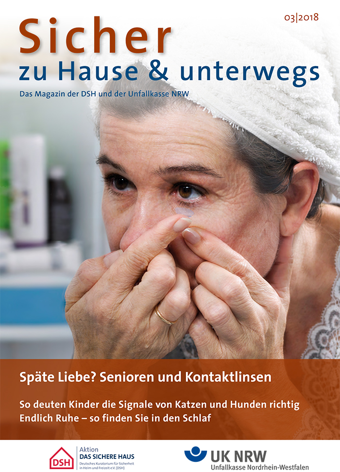 Titelblatt der Ausgabe 03/2018 des Magazins 'Sicher zu Hause & unterwegs', herausgegeben von der DSH und der Unfallkasse NRW. Eine ältere Frau setzt sich gerade Kontaktlinsen ein. Der Titel und mehrere Artikelvorschauen stehen auf dem Cover. Unten sind die Logos von Aktion Das Sichere Haus (DSH) und der Unfallkasse Nordrhein-Westfalen (UK NRW) abgebildet. Themen sind unter anderem die richtige Interpretation von Signalen von Haustieren wie Katzen und Hunden, sowie Tipps für einen besseren Schlaf.