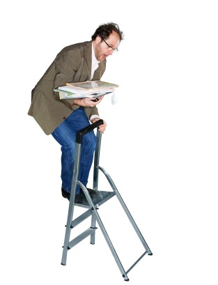 Ein Mann im Anzug steht auf einer kleinen Leiter und balanciert unsicher mehrere Akten in den Händen. Die Situation weist auf Risiken im Arbeitsschutz hin, die durch unsachgemäße Nutzung von Leitern entstehen können. Diese Darstellung betont die Bedeutung von Sicherheitsmaßnahmen und Prävention am Arbeitsplatz, wie sie von der Unfallkasse NRW gefördert werden.