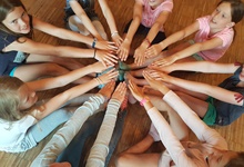 Kinder sitzen im Kreis und strecken die Hände zur Mitte.