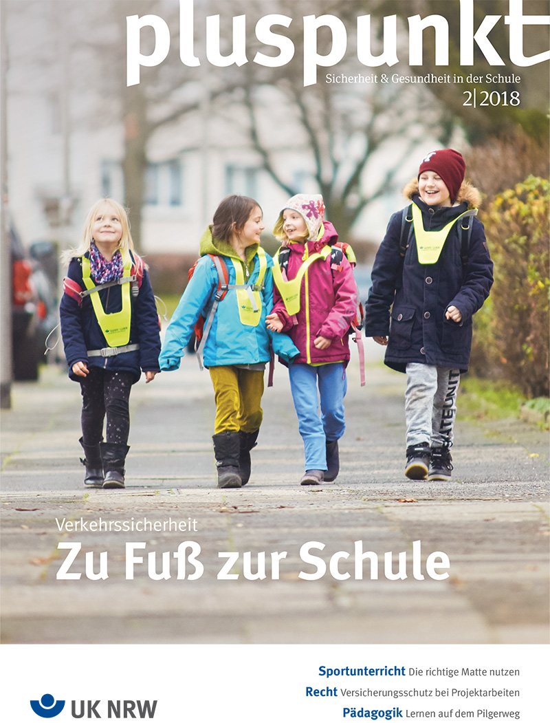 Kinder mit Warnwesten laufen nebeneinander auf dem Gehweg.