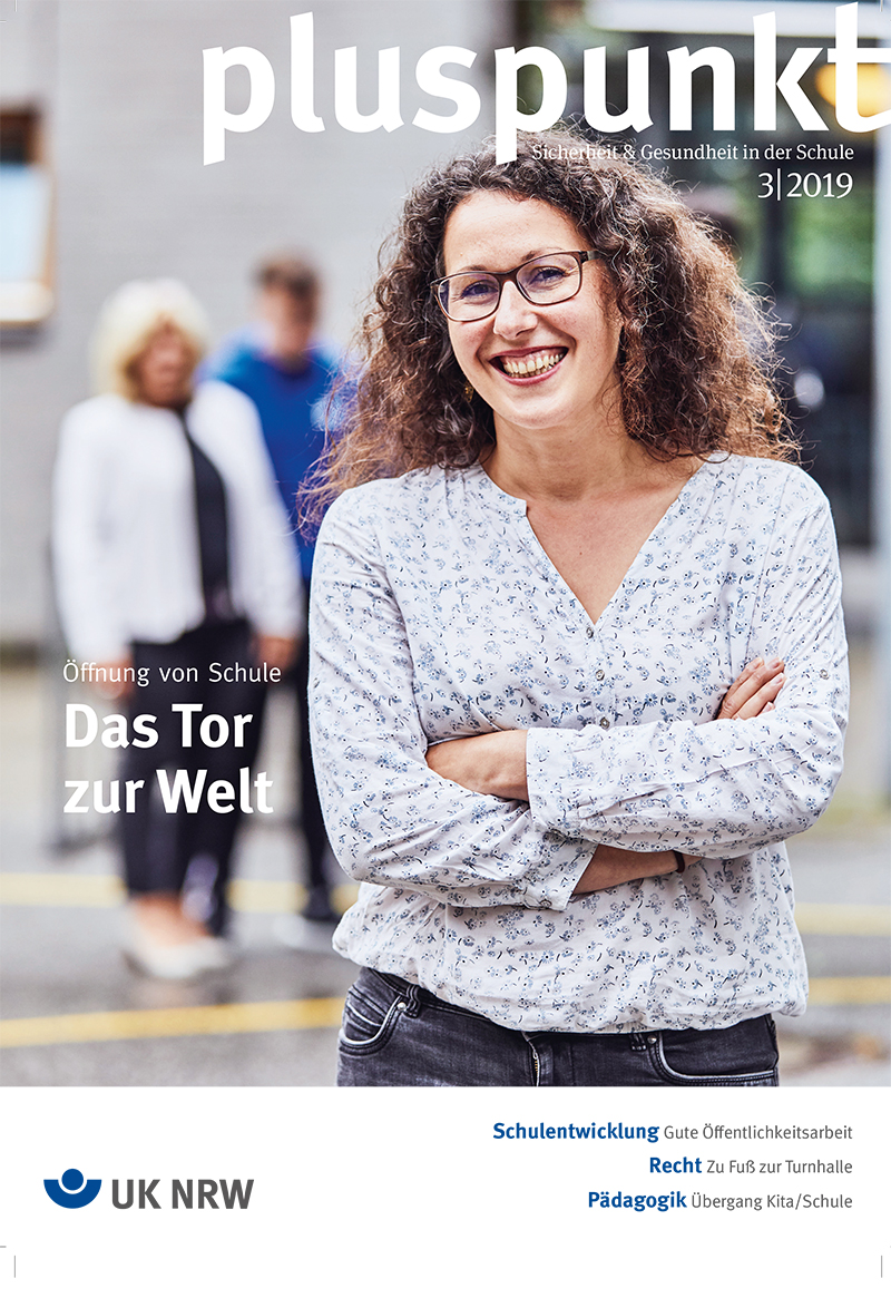 Titelbild des Magazins 'pluspunkt' mit dem Schwerpunkt auf Schule und Gesundheit, Ausgabe 3/2019. Eine Frau mit lockigem Haar und Brille lächelt in die Kamera, gekleidet in einem blauen Blumenmusterhemd. Im Hintergrund sind zwei unscharfe Personen zu sehen, eine in Blau und Weiß gekleidet, die andere in einem weißen Oberteil. Der Titel 'Öffnung von Schule - Das Tor zur Welt' ist auf dem Bild platziert. Unten links befindet sich das Logo der Unfallkasse NRW. Das Thema Arbeitsschutz und Prävention in Schulen wird hervorgehoben, passend zur Zielsetzung der Unfallkasse NRW zur Verbesserung der Sicherheitsstandards im Bildungsbereich.