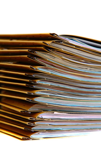 Ein hoher Stapel Aktenordner, geordnet und übereinander gestapelt. Die Aufnahme zeigt die Akten von der Seite, wodurch die Vielzahl der Akten und deren Dicke sichtbar werden. Das Bild könnte im Kontext von Arbeitsschutz und Prävention bei der Unfallkasse NRW auf ordnungsgemäße Dokumentation und Verwaltung von Sicherheitsunterlagen hinweisen.