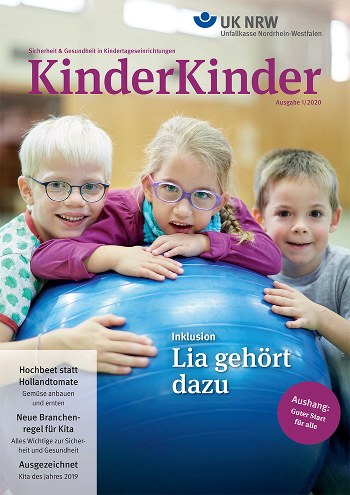 Drei Kinder in einem hellen, freundlichen Kita-Raum spielen gemeinsam mit einem großen blauen Gymnastikball. Ein Mädchen mit Brille steht in der Mitte, lächelt und hält den Ball mit zwei Jungen, die sie flankieren. Im Hintergrund unscharf Kinder und Regale. Oben steht 'KinderKinder' und unten der Slogan 'Inklusion: Lia gehört dazu'. Die Zeitschrift betont Themen wie Sicherheit und Gesundheit in Kindertageseinrichtungen, herausgegeben von der Unfallkasse Nordrhein-Westfalen.