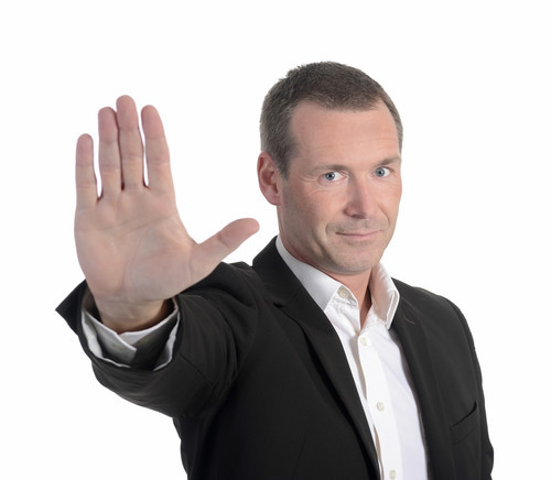 Mann in Anzug hebt Hand zur Stopp-Geste.