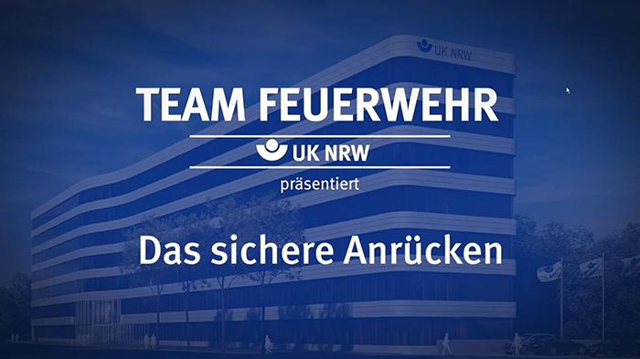 Text auf Gebäude: Team Feuerwehr, UK NRW präsentiert Das sichere Anrücken.