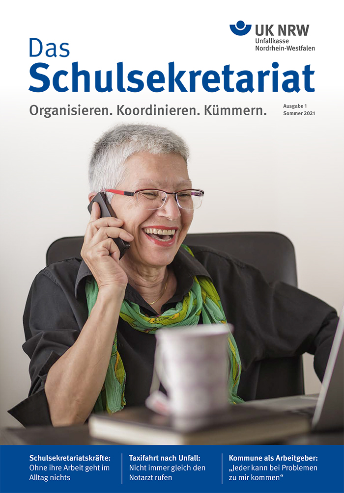 Eine fröhliche Person hält ein Telefon am Ohr und lächelt. Sie sitzt in einem Büro und trägt eine Brille sowie einen Schal. Der obere Teil des Bildes zeigt das Logo der Unfallkasse Nordrhein-Westfalen und den Titel 'Das Schulsekretariat'. Darunter befinden sich die Schlagzeilen: 'Schulsekretariatskräfte: Ohne ihre Arbeit geht im Alltag nichts', 'Taxifahrt nach Unfall: Nicht immer gleich den Notarzt rufen', 'Kommune als Arbeitgeber: Immer bei Problemen zu mir kommen'. Das Bild vermittelt eine positive Atmosphäre und verdeutlicht Themen des Arbeitsschutzes sowie Prävention.