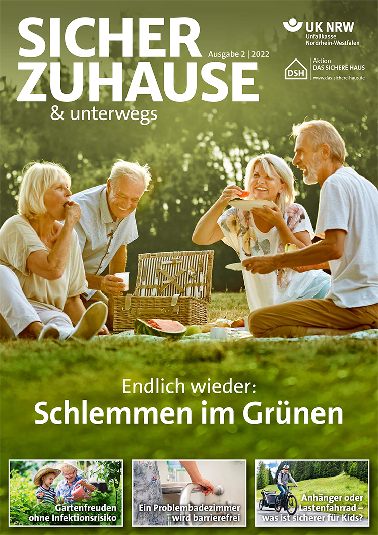 Das Bild zeigt drei ältere Personen und einen Jungen, die an einem Tisch im Freien sitzen. Sie essen und unterhalten sich entspannt in einem grünen Garten. Daneben sind Titel und Themen der Zeitschrift sichtbar: 'Sicher Zuhause & unterwegs', 'Endlich wieder: Schlemmen im Grünen'. Es gibt Hinweise zur Unfallkasse NRW und zur Prävention in Bezug auf Arbeitsschutz und Sicherheit im Alltag. Die Themen umfassen Gartengenuss ohne Infektionsrisiko, barrierefreies Problembadezimmer und die Sicherheit von Fahrradanhängern für Kinder.
