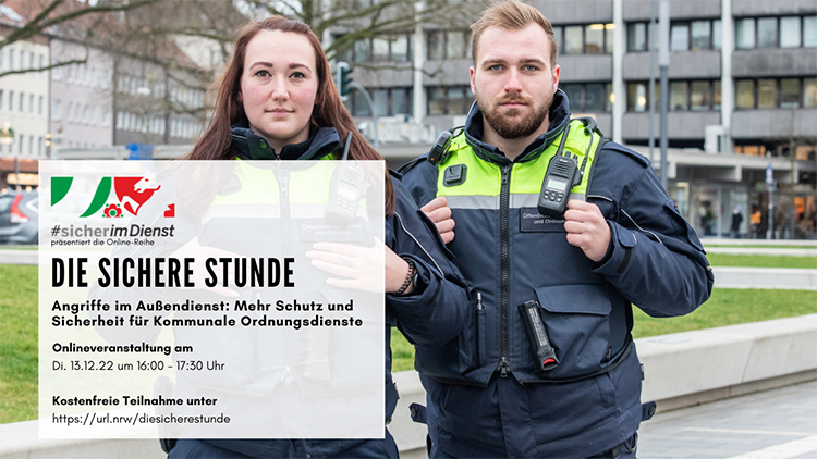 Zwei Personen in Sicherheitsuniformen stehen nebeneinander auf einem Gehweg vor einem städtischen Gebäude. Sie tragen gelb-blaue Jacken mit Funkgeräten an der Brust. Im Vordergrund befindet sich eine Texttafel mit Informationen zur Veranstaltung 'Die sichere Stunde' über Schutz und Sicherheit für Kommunale Ordnungsdienste, die am 13.12.22 online stattfindet. Der Hintergrund zeigt ein modernes Bürogebäude und kahle Bäume im Winter.