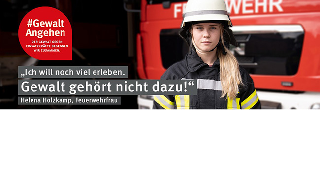 Eine Feuerwehrfrau in Uniform und Helm steht vor einem Feuerwehrauto. Links oben ist ein rotes Logo mit der Aufschrift '#Gewalt Angehen'. Daneben der Text: 'Ich will noch viel erleben. Gewalt gehört nicht dazu!' gefolgt von dem Namen Helena Holzkamp. Die Kampagne richtet sich gegen Gewalt gegenüber Einsatzkräften und betont Arbeitsschutz und Prävention.