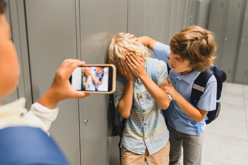 Das Bild zeigt einen Jungen der aggeressiv einen anderen Schüler angreift