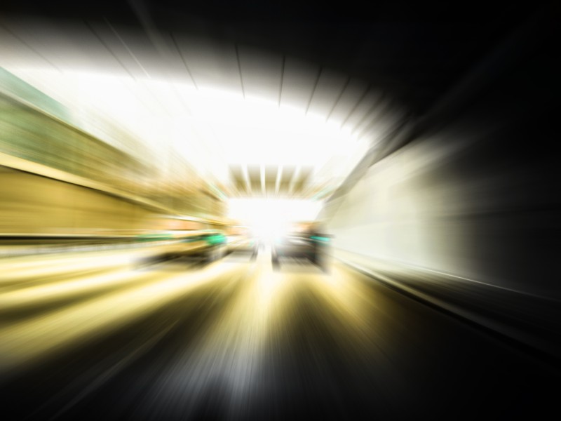 Das Bild zeigt verschwommene Lichter und Bewegungen in einem Tunnel, die auf eine schnelle Fahrt hinweisen. Es illustriert die Bedeutung von Vorsichtsmaßnahmen und Arbeitsschutz, um Unfälle in Situationen hoher Geschwindigkeit und eingeschränkter Sicht- oder Bewegungsfähigkeit zu verhindern. Das Bild ist relevant für die Unfallkasse NRW im Kontext von Unfallverhütung und Prävention im Straßenverkehr.
