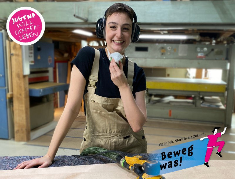 Das Bild zeigt eine junge Frau mit Gehörschutzausrüstung an der Werkbank