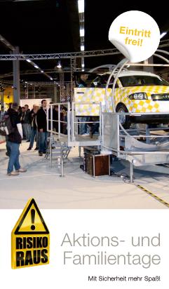 Ein gelb-weiß kariertes Auto steht auf einem rotierenden Fahrsimulator in einer Messehalle. Mehrere Menschen beobachten die Demonstration. Ein Schild mit der Aufschrift 'Eintritt frei!' und ein weiteres Schild mit 'Risiko Raus' sind sichtbar. Die Veranstaltung wirkt wie ein Aktionstag, der vom Kontext auf Arbeitsschutz und Prävention ausgerichtet ist.